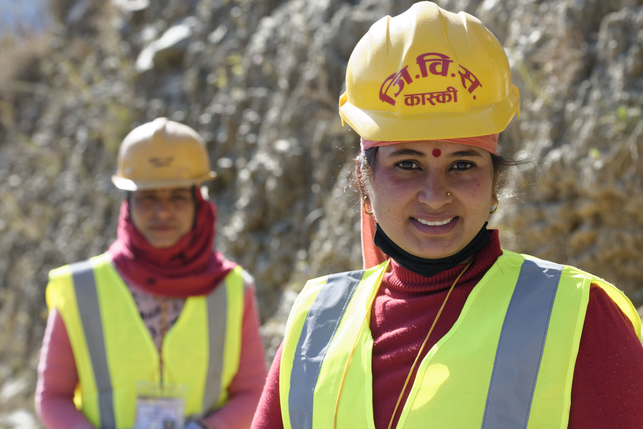Two Nepalese women construction workers are wearing hard hats