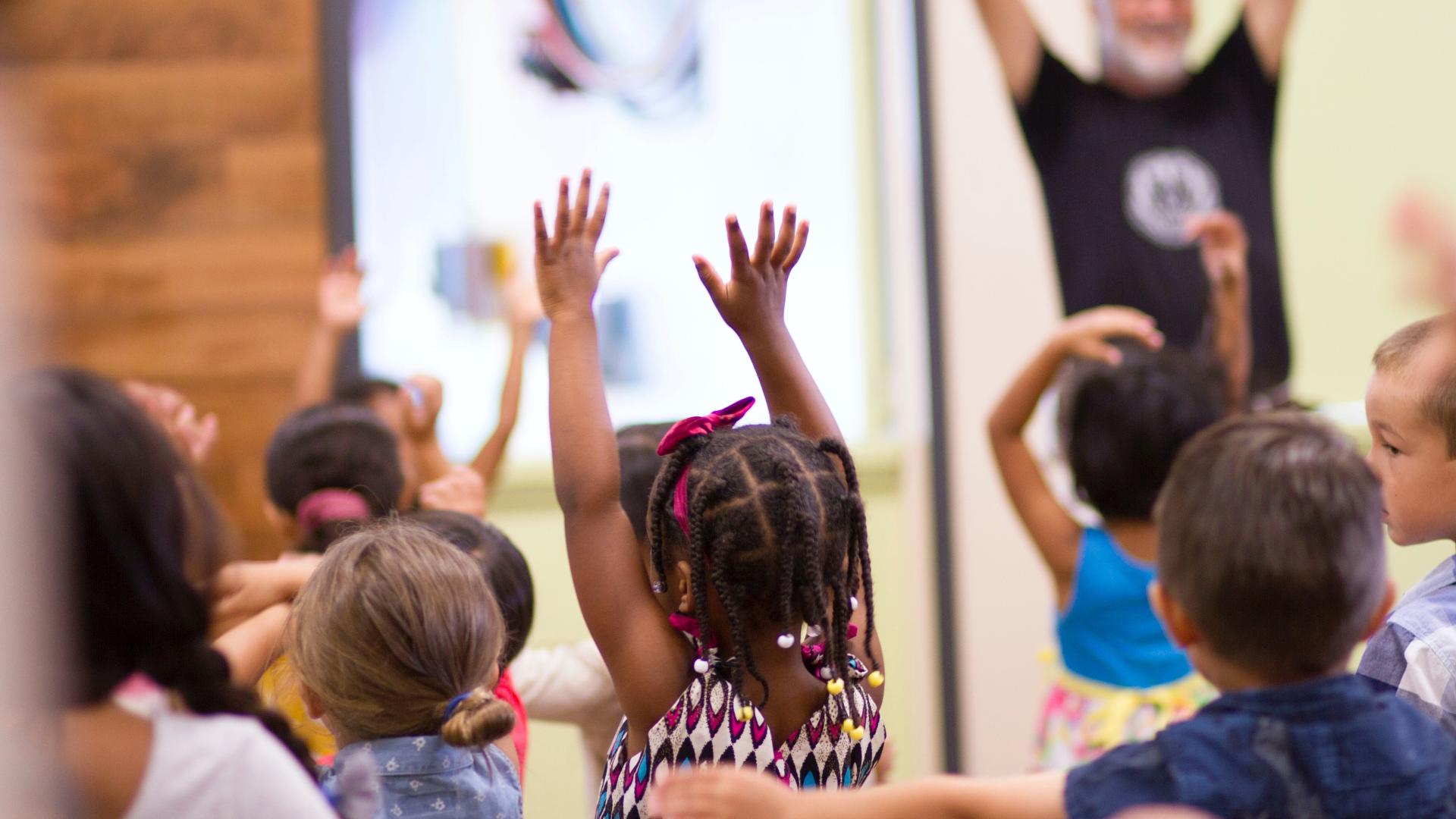 Children in a classroom are raising their hands