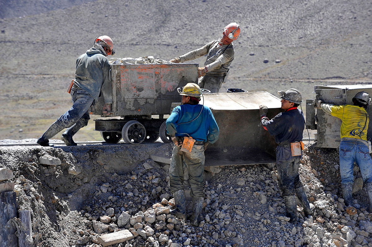 Group of men securing cart with rocks in outside mine
