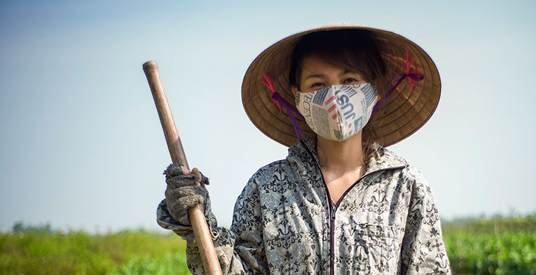Local female Vietnamese farmer in field with mask hat and stick copyright ILO/Maxime Fossat
