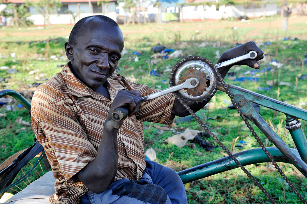 Elderly black man with handicap on bicycle with pedals by hand