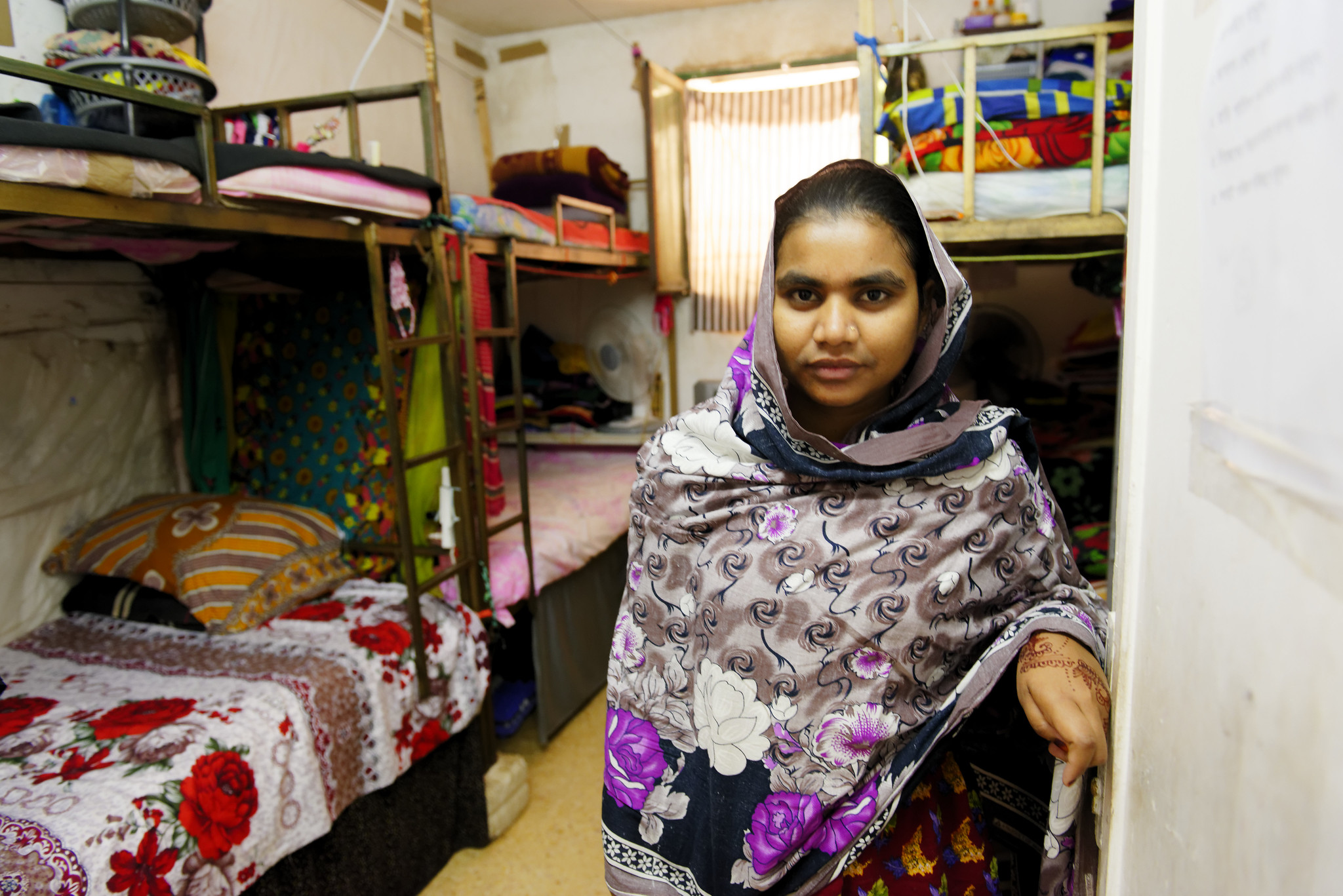 A Bangladeshi garment worker is seen standing in the room she shares with other seven colleagues in a factory dormitory in Jordan