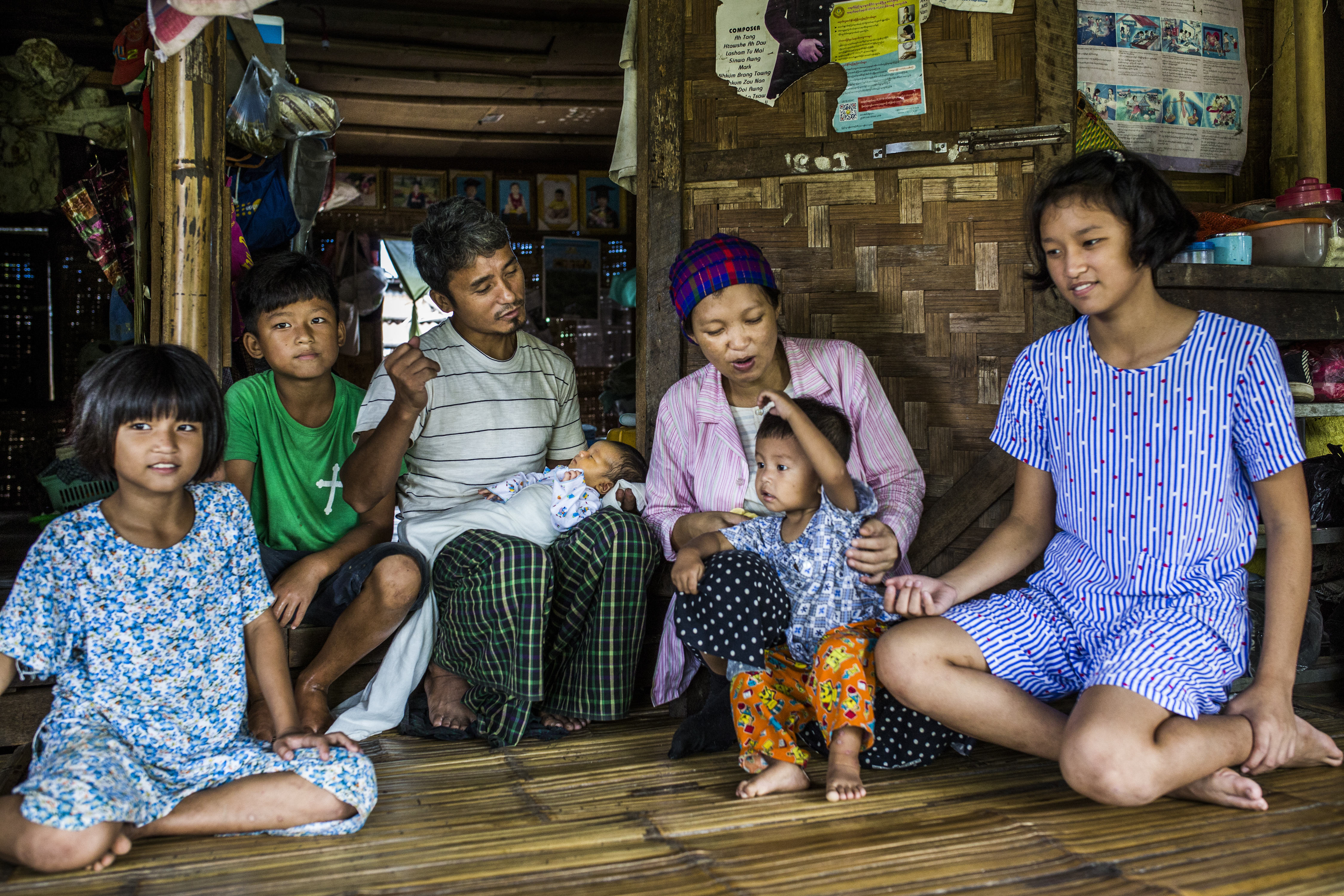 Parents and 5 children of Kachin family kneeling in their home