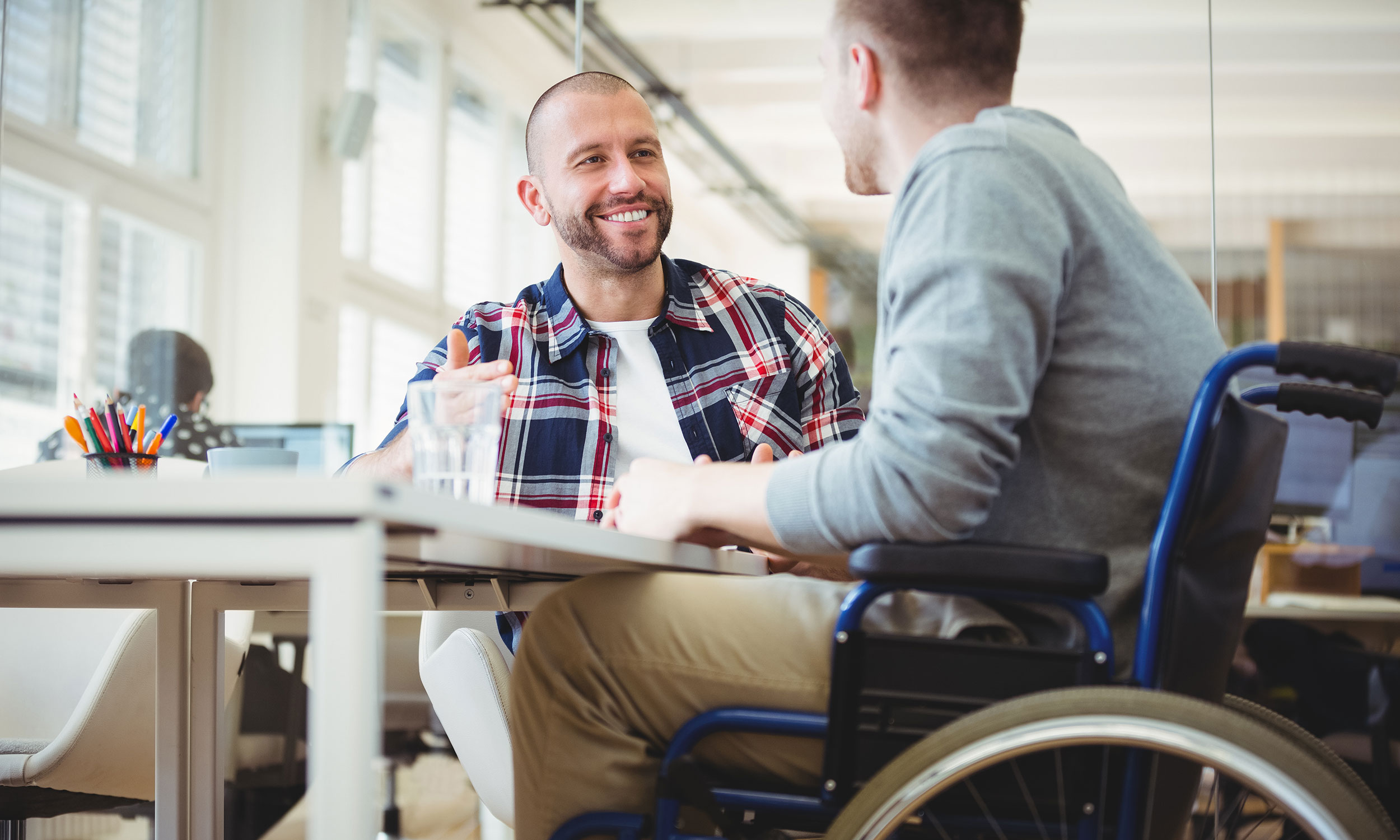 Two men talking around a table, one in a wheelchair