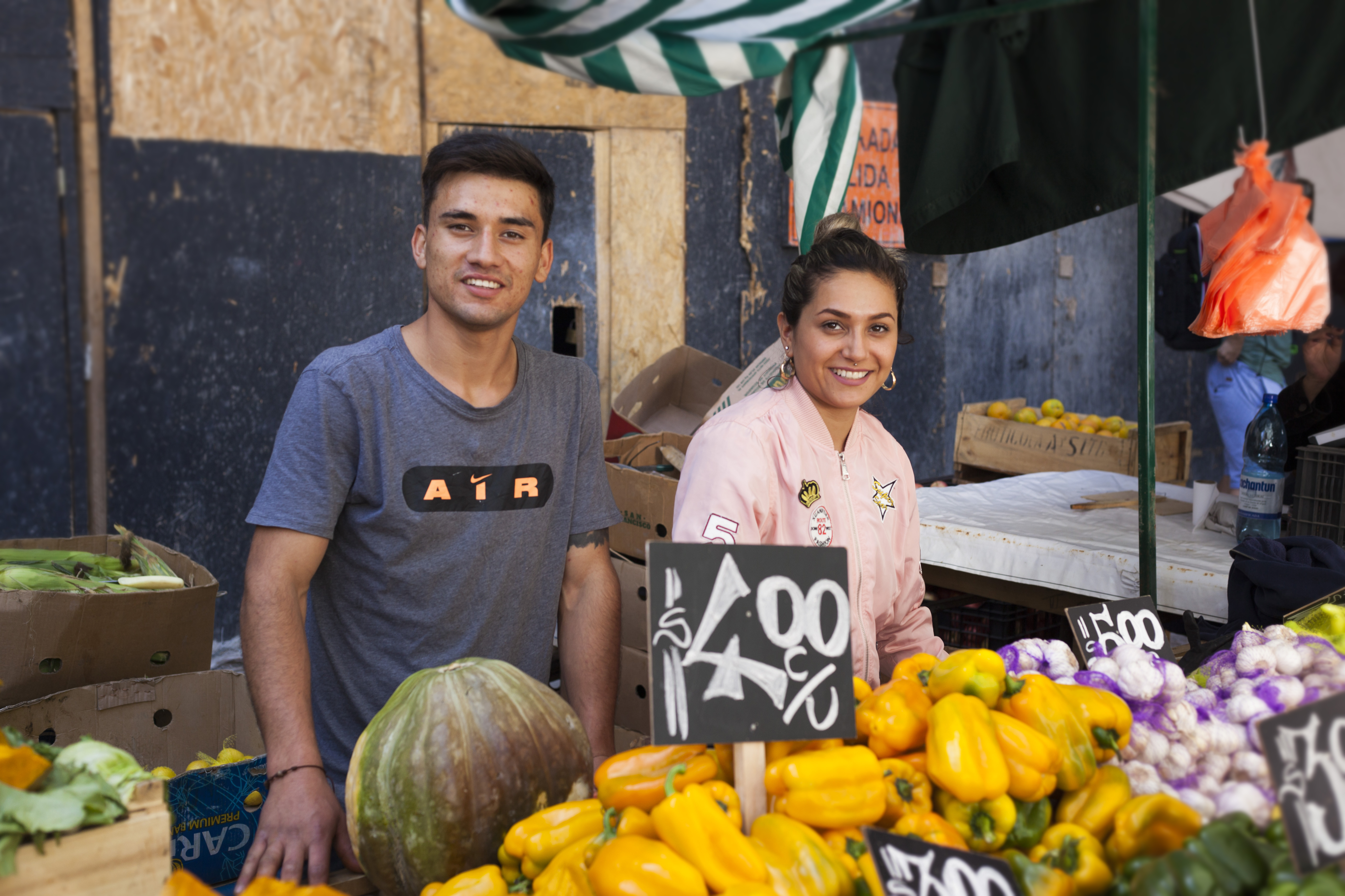 Image of young man and woman at vegetable market stall in Santiago