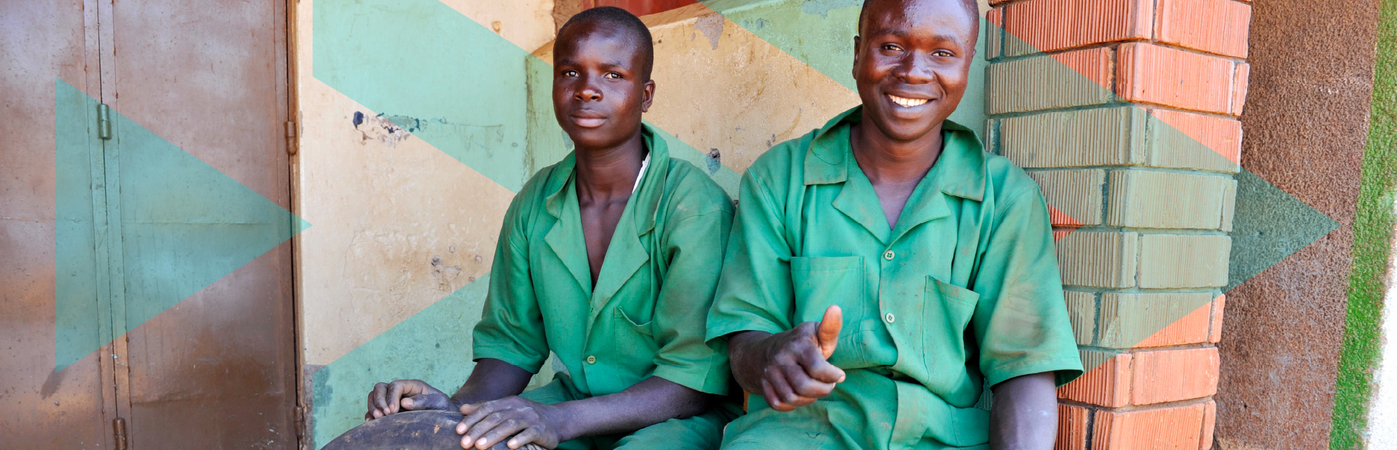 Two black young mechanics in green overalls with tyre in the no man's land near the Busia border from Kenya to Uganda. 