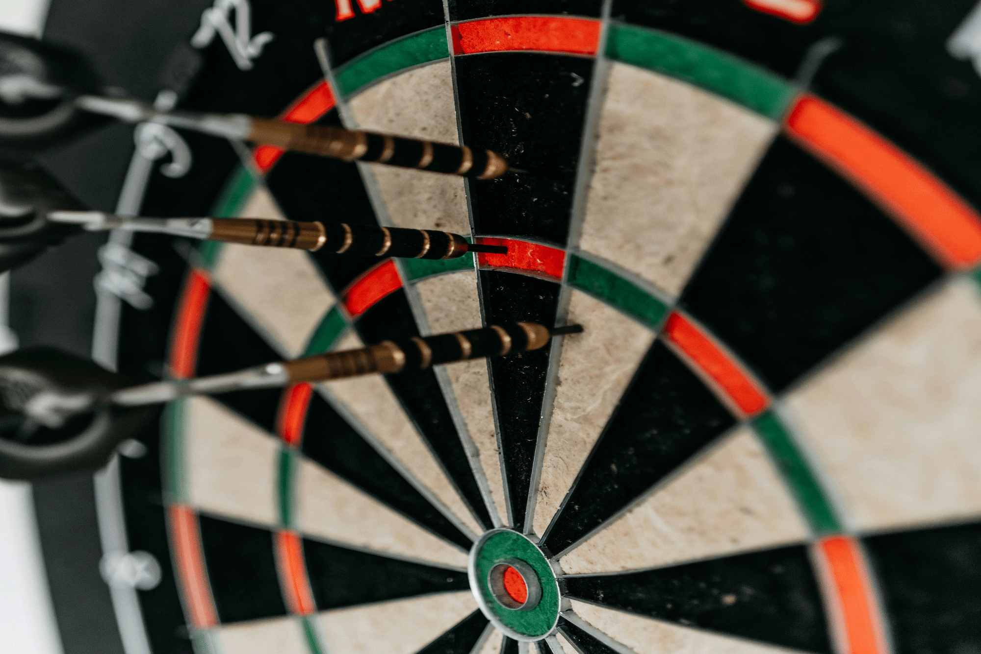 dart board with white black red and green sections and three darts