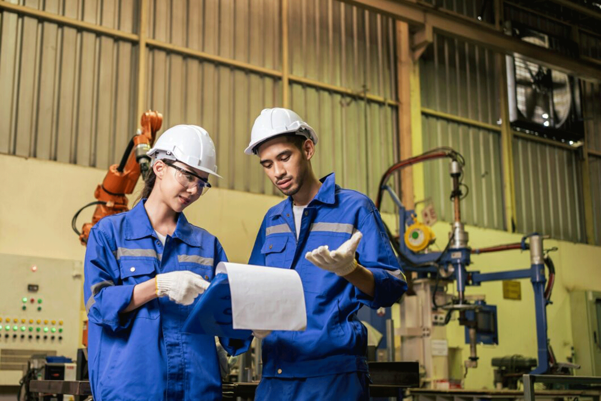 Asian male and female industrial worker working in manufacturing plant.