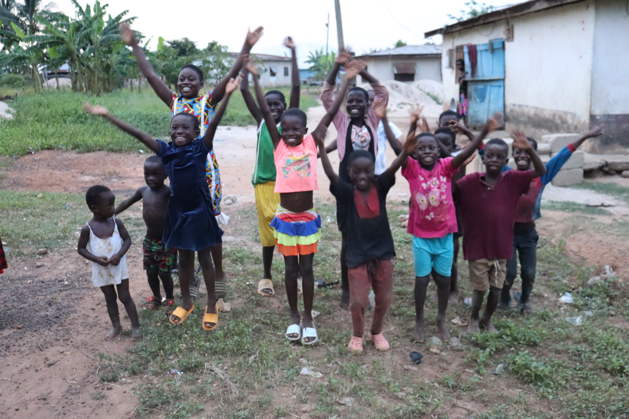 Group of young black children in village smiling and jumping