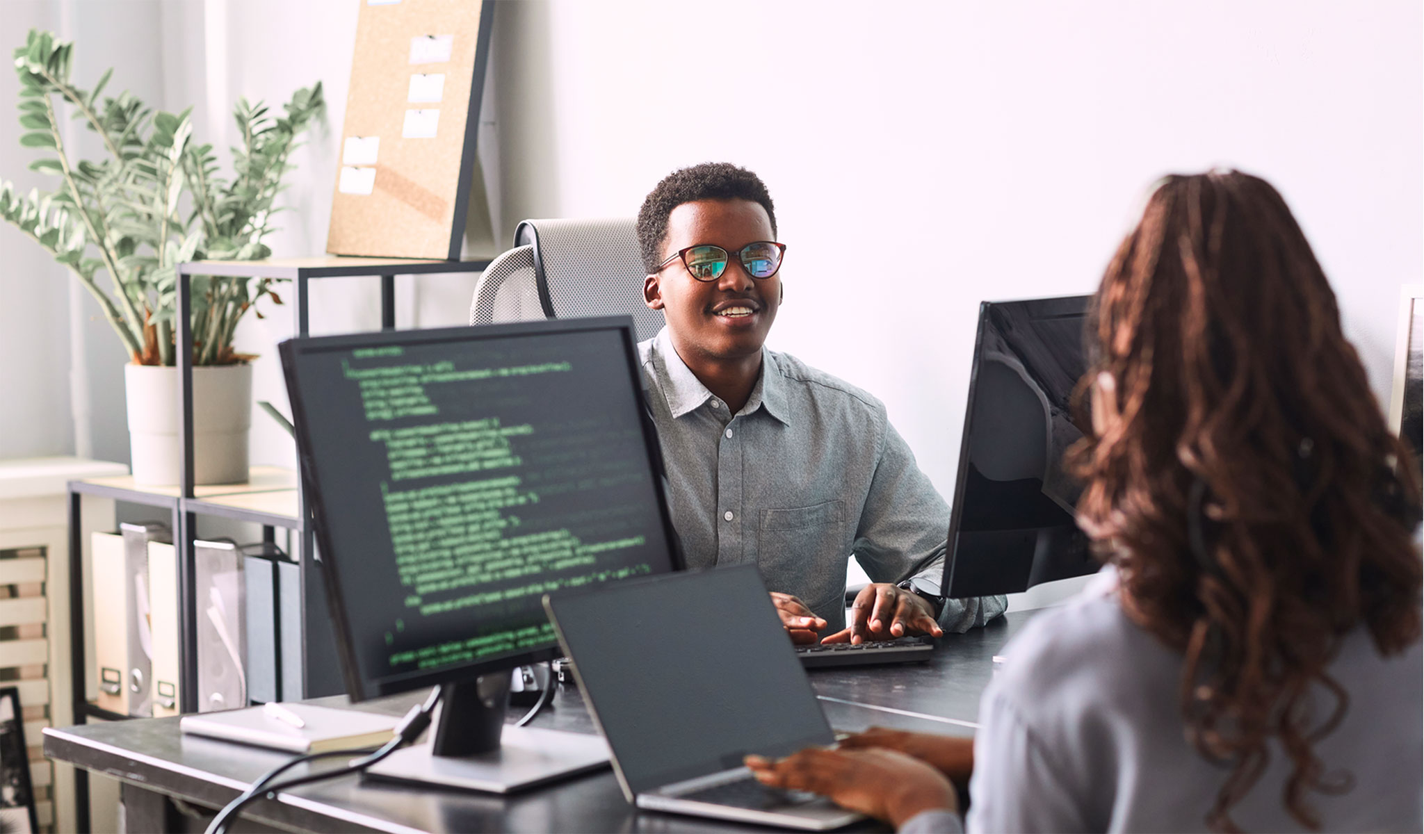 Two young Africans work on computers in an office