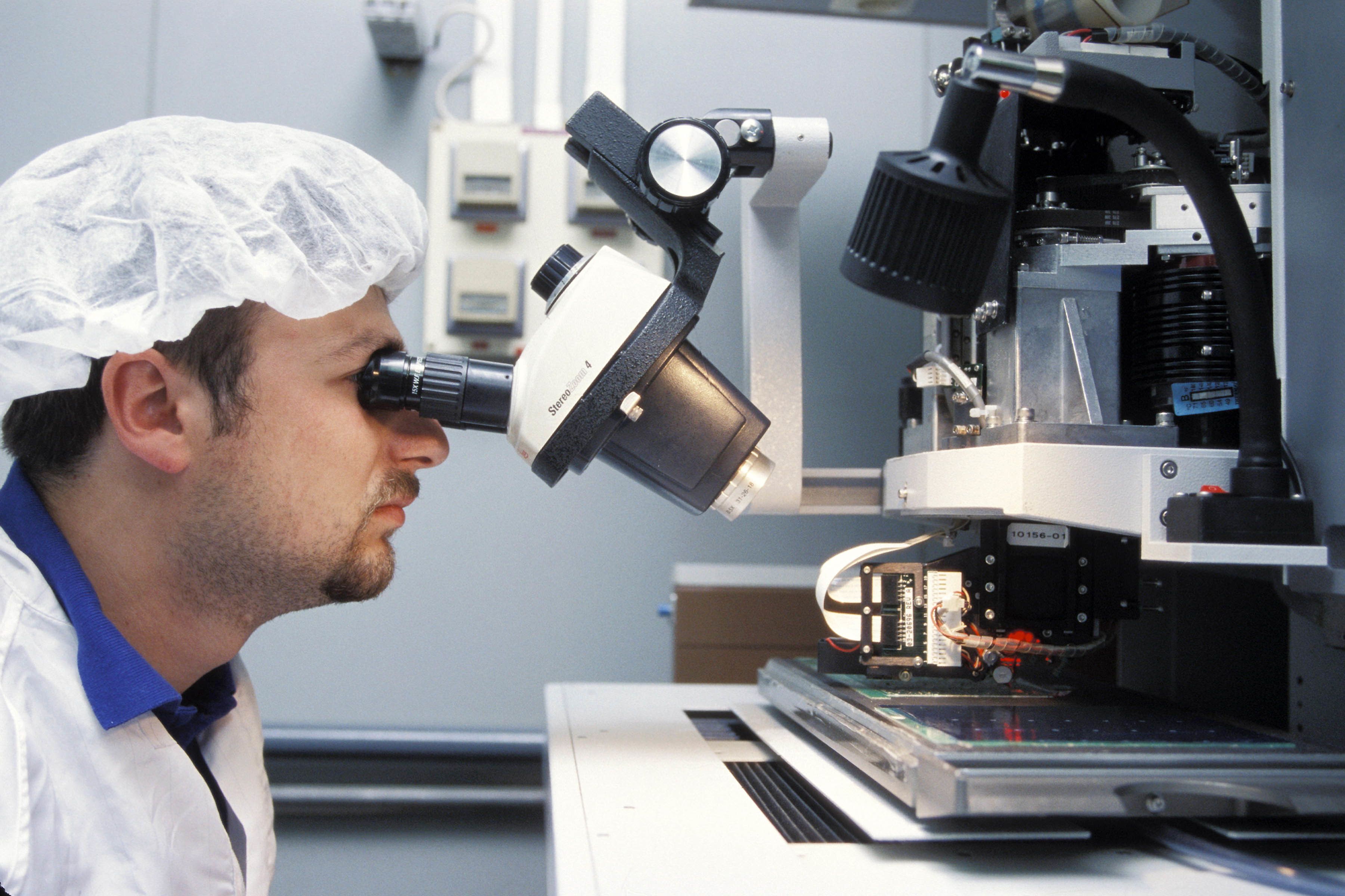 Man looking through a microscope at a factory