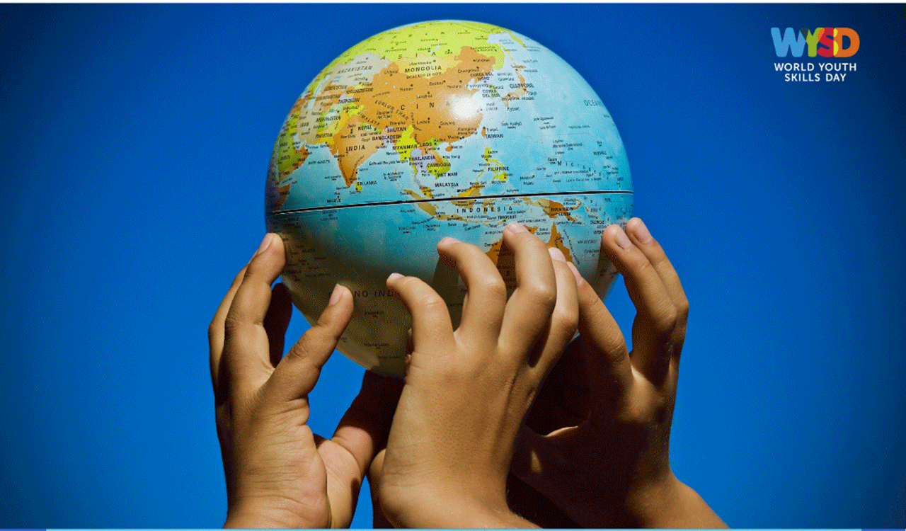 close up of three hands holding up a metal globe of the earth