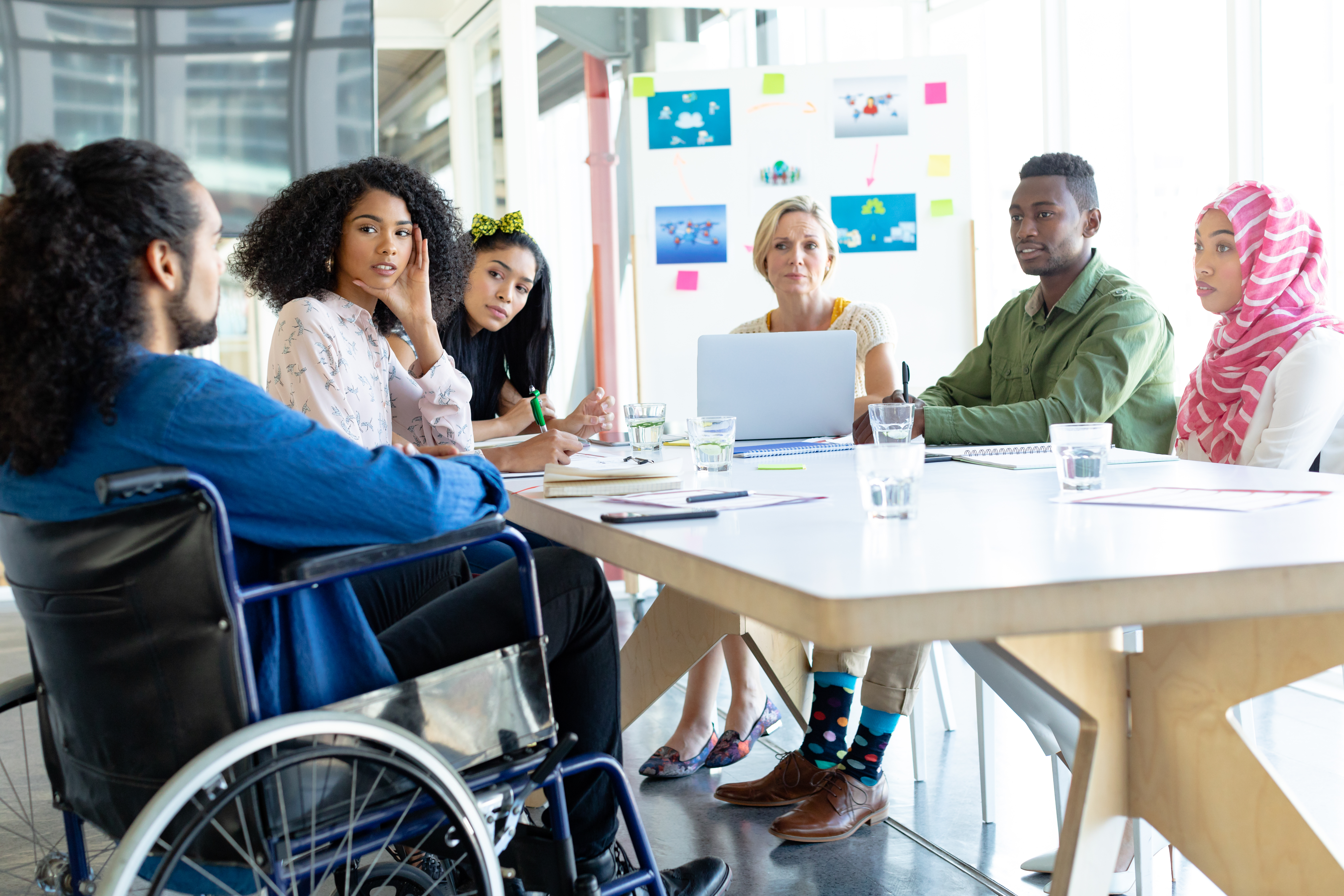 Business People discussing with each other around desk one with wheelchair iStock-1155692275