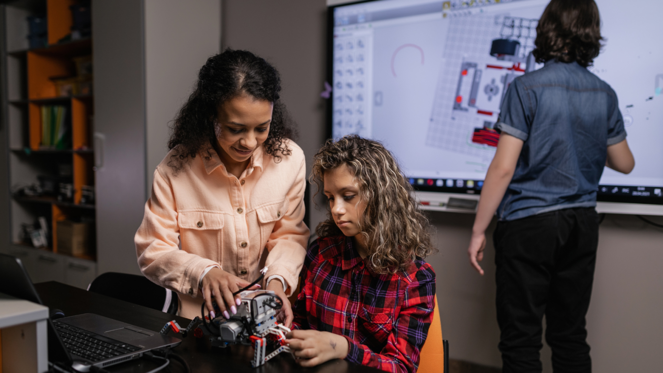Two young female students learn to build a robot