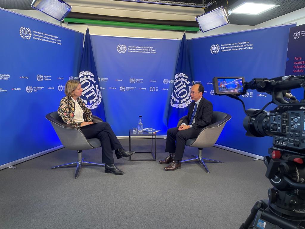 Anchor Sophy Fisher and ILO economist Sangheon lee talk on a TV set