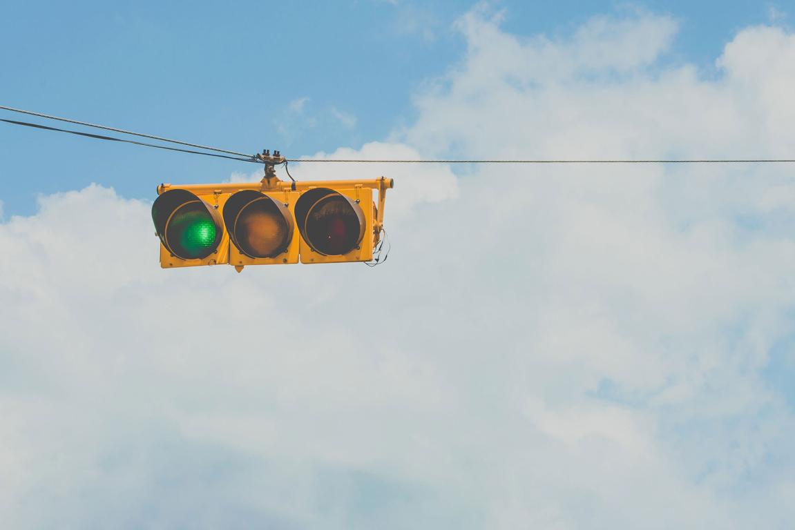 Horizontal yellow traffic light on green with bright cloudy sky - Carlos Alberto Gómez Iñiguez https://unsplash.com/photos/jqiAU_JQGyk