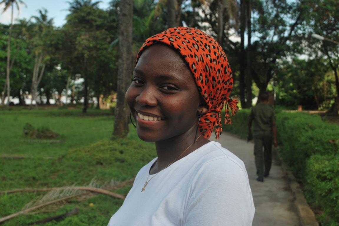 Close up of black lady smiling with red and pattered head scarf in a park