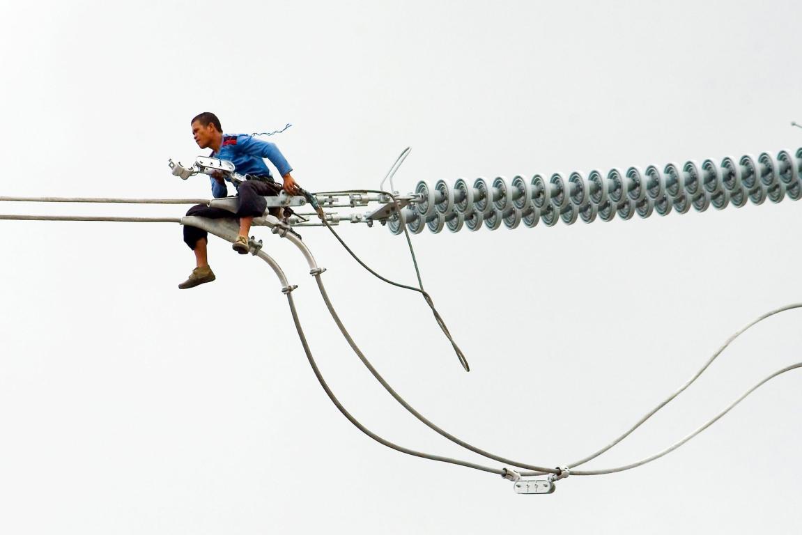 Man sitting on suspended electric wires