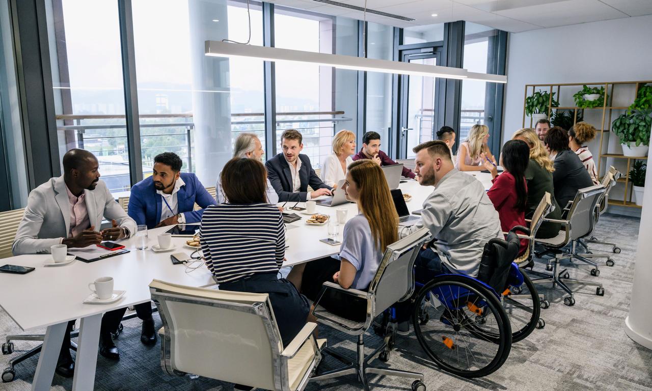 Two men talking around a table, one in a wheelchair