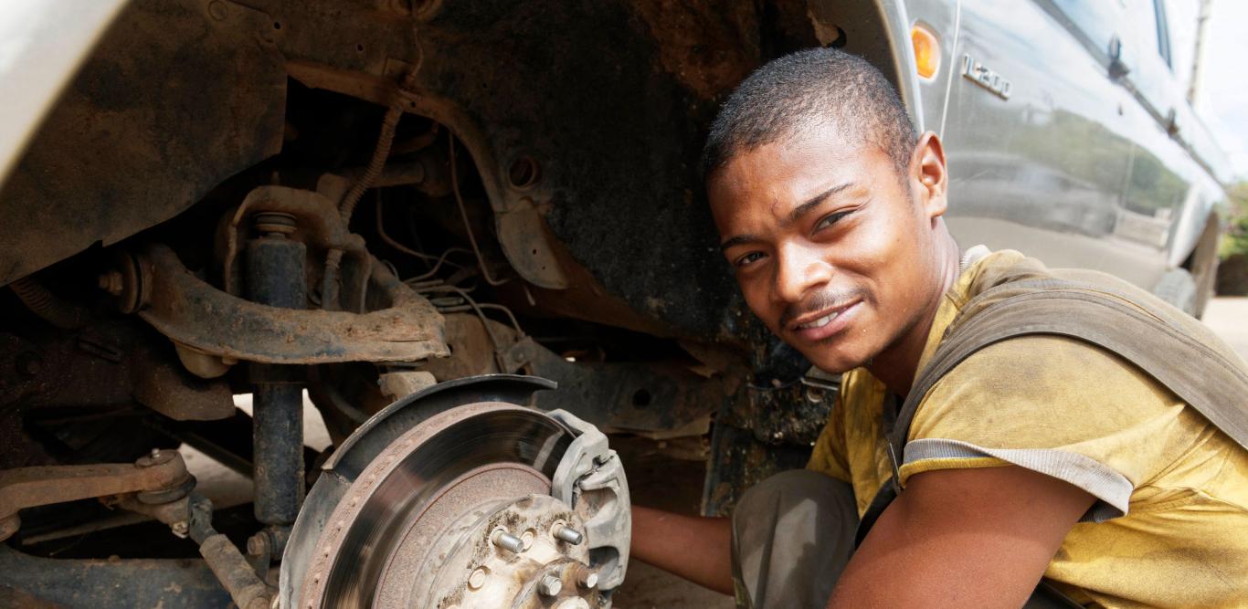 Young African worker repairing a car.