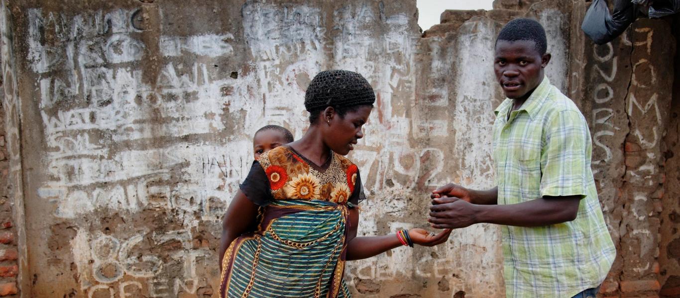 Woman carrying her young child while selling fries on a market in the capital of Malawi, Lilongwe.