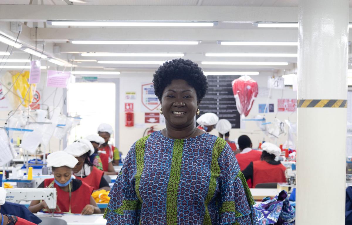 Black lady with colourful top and machinists working in the backgroud