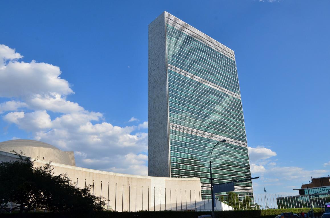 Tall rectangular building with blue sky with clouds behind