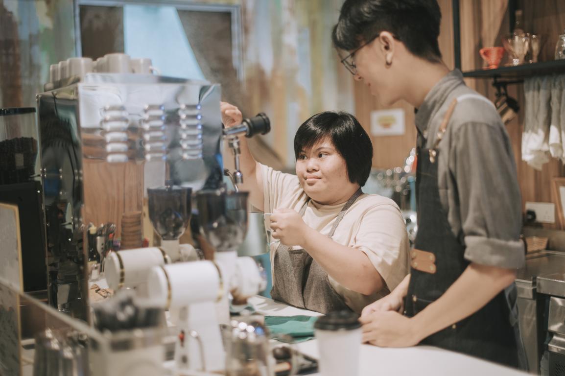 A young disabled worker works in a bar under the supervision of a colleague