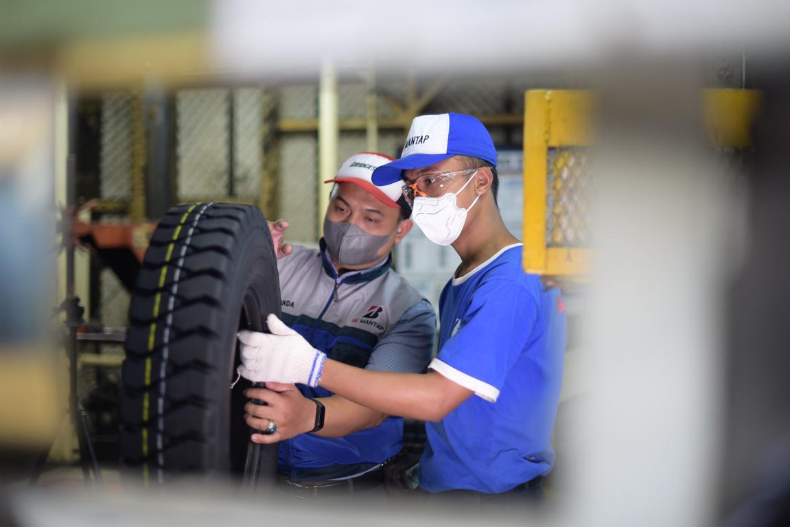 Two men with baseball caps checking a tyre