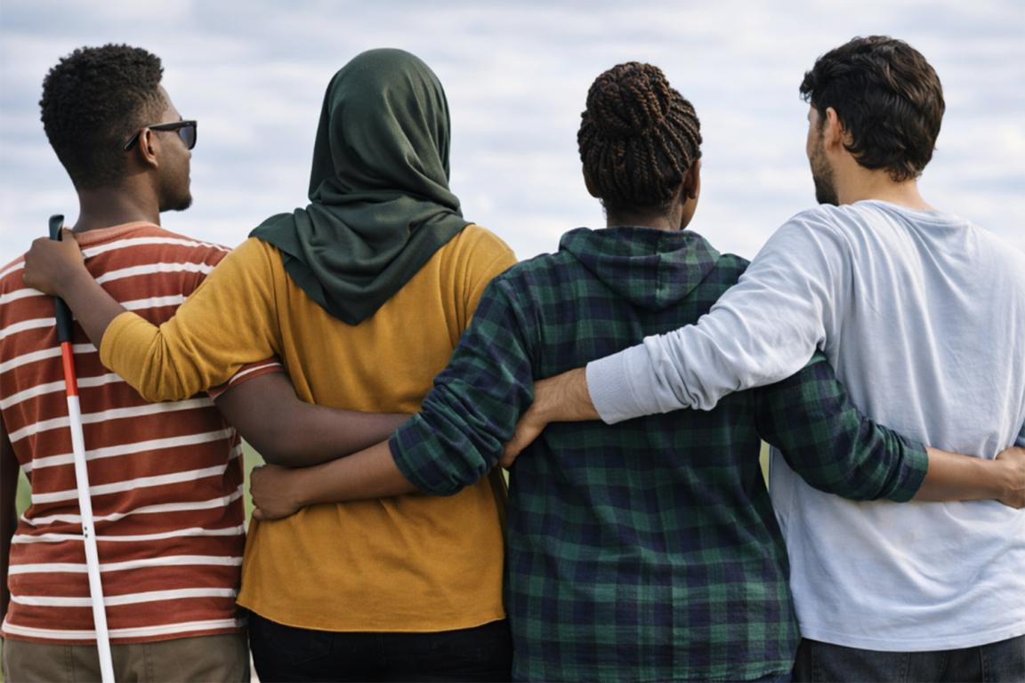 Two women and two men are standing close together, seen from behind