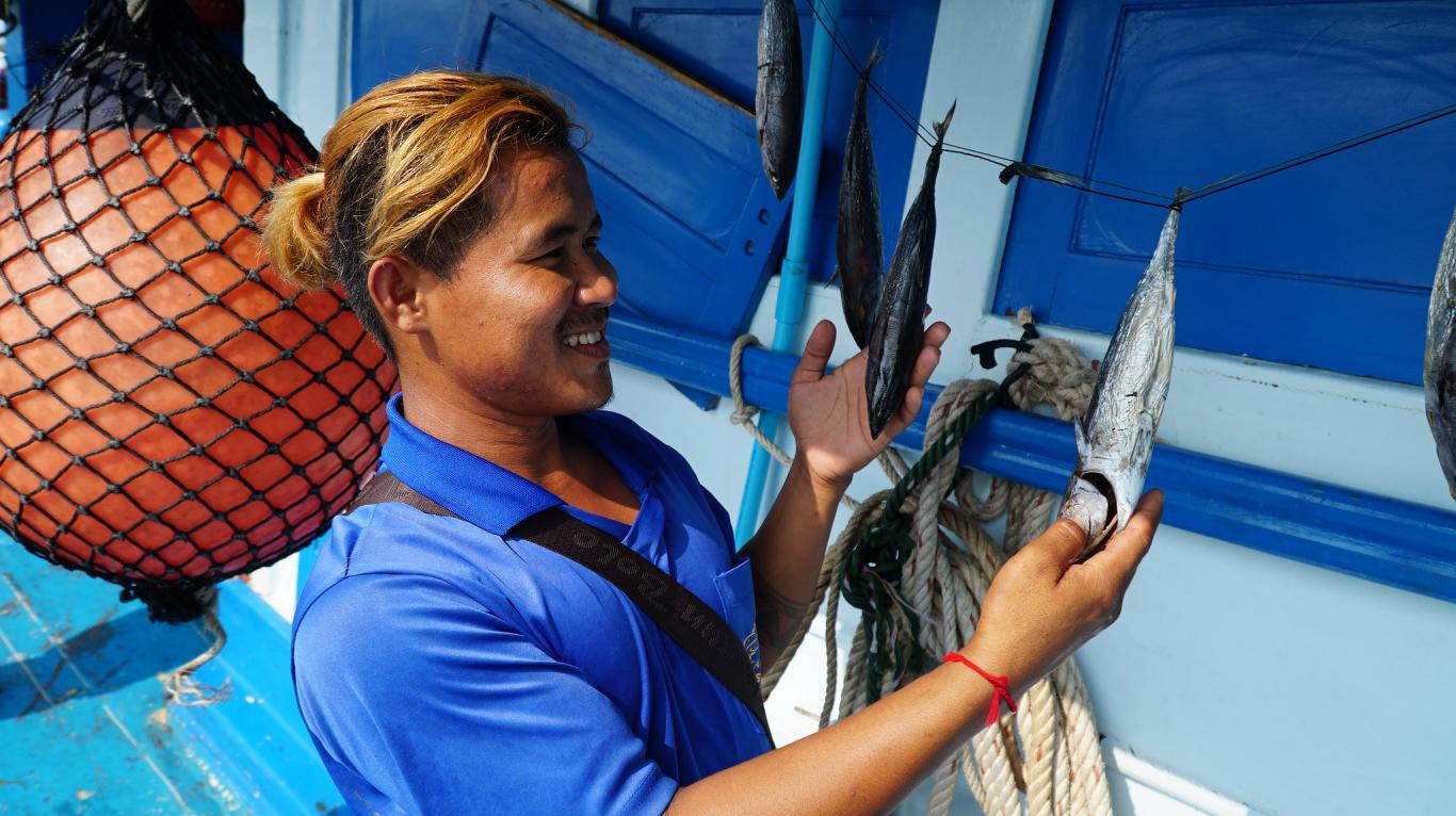 Male fisher on fishing boat showing two fish on a line