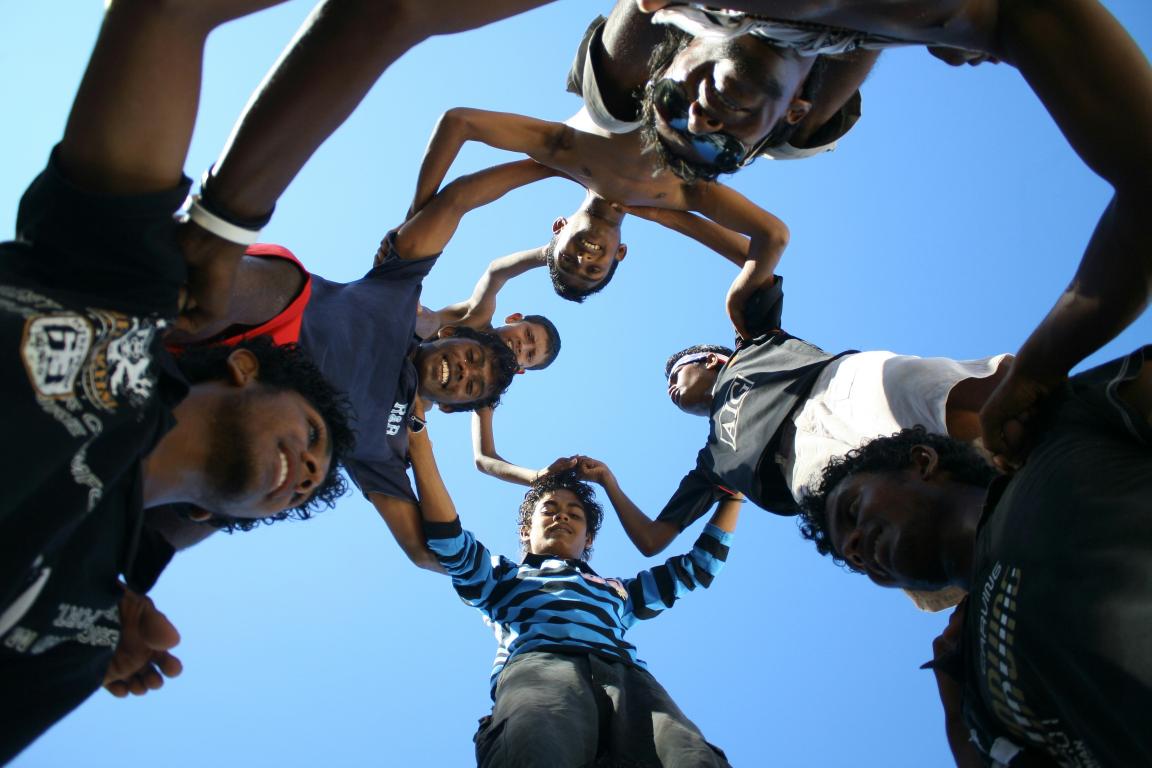 a group of young men standing in a circle under a blue sky