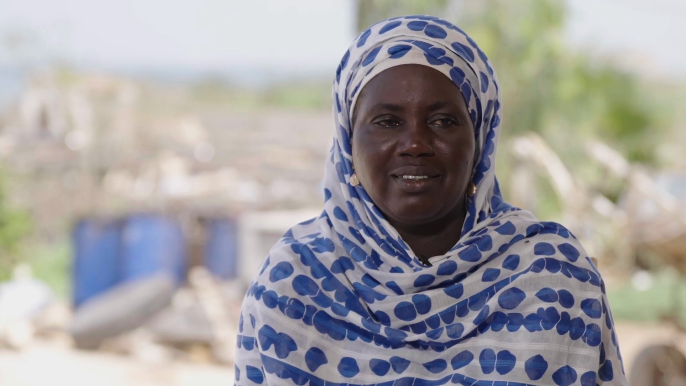 A woman with a head scarf looks at the camera