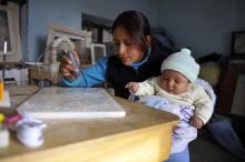 Mother carving tombstones while taking care of her baby. Potosí, Bolivia.