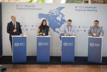 4 people stood up with microphones talking at a panel event