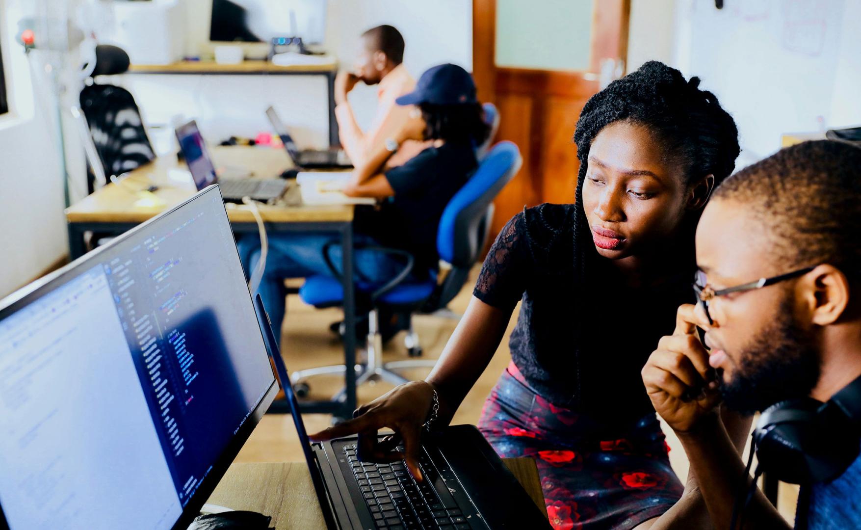 A young African woman and man sitting in front of monitor 
