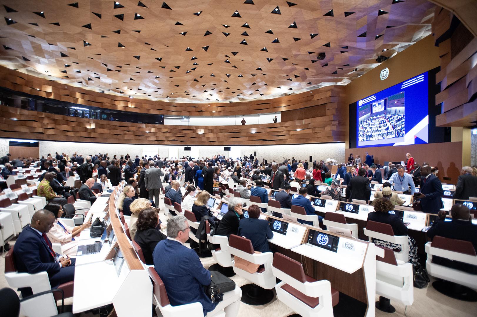 Conference room full of delegates sitting listening to speeches